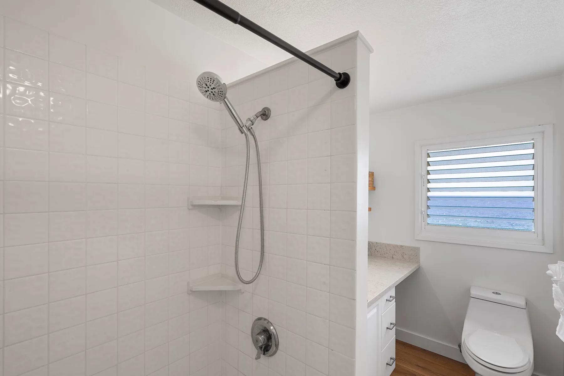 A tiled bathroom with a shower, vanity, and toilet.