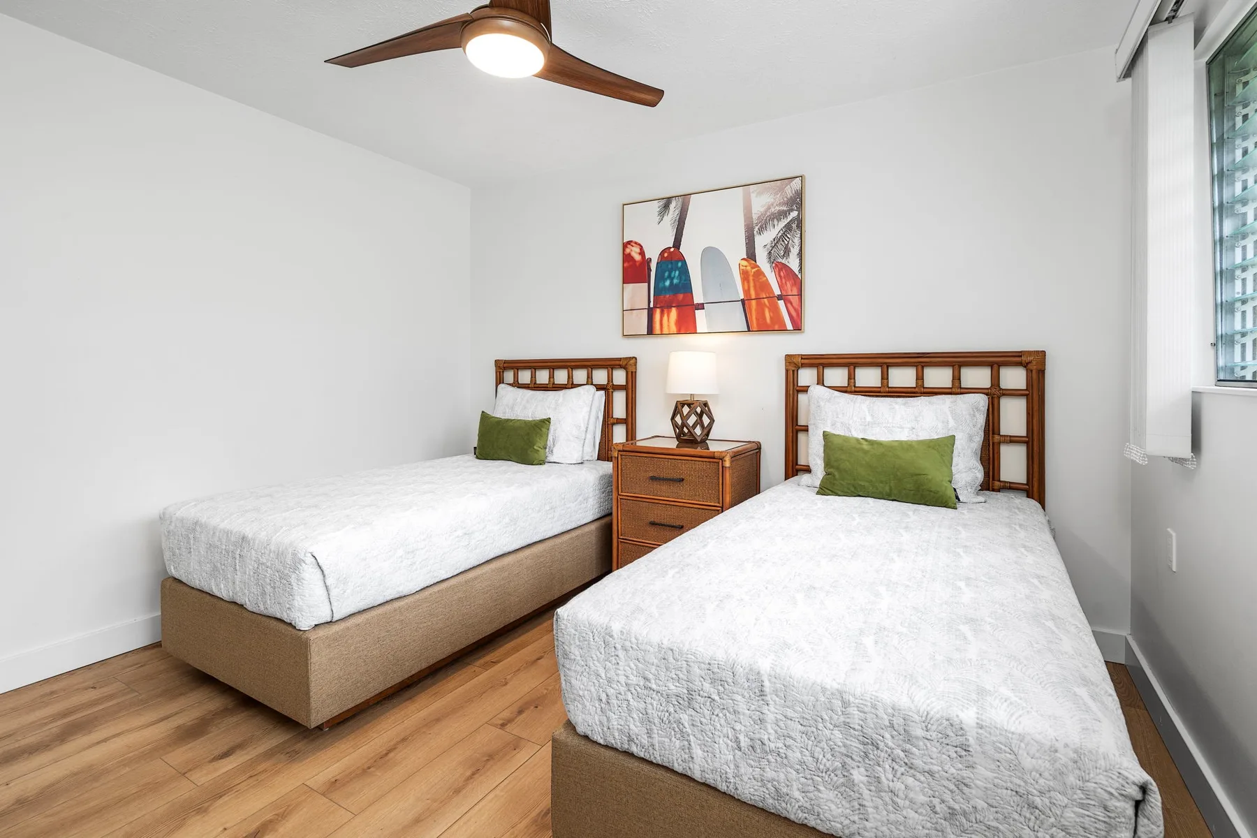 A bright bedroom with two beds and a colorful framed artwork.