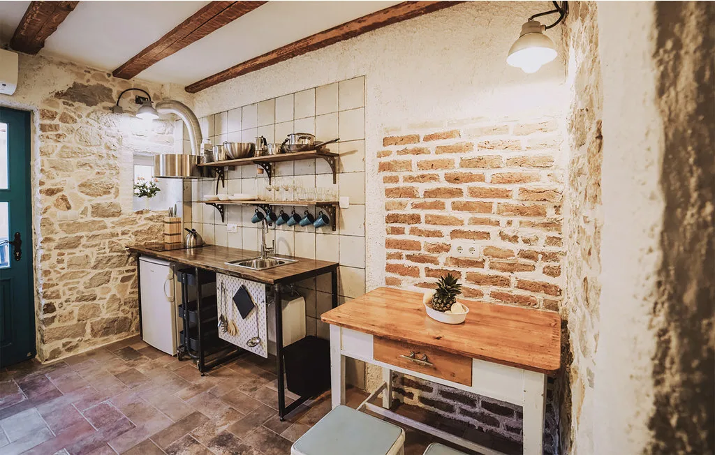 Una cocina rústica con estantes abiertos, un salpicadero de azulejos y una mesa de trabajo de madera.