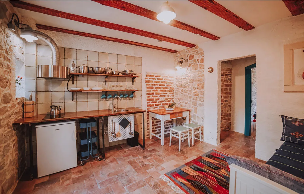 Una cocina rústica con estantes abiertos, una mesa pequeña y vigas expuestas.