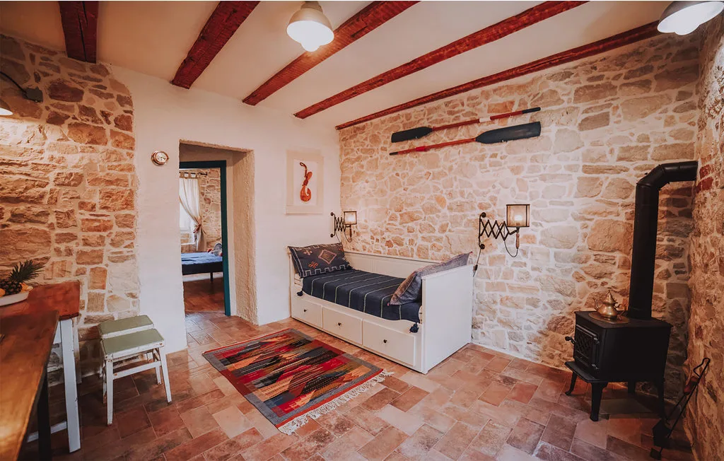 Una sala con paredes de piedra, un banco acolchado y una pequeña estufa.