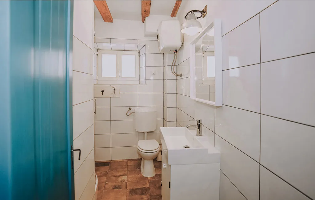 Un baño alicatado con lavabo, inodoro y cortina de ducha azul.