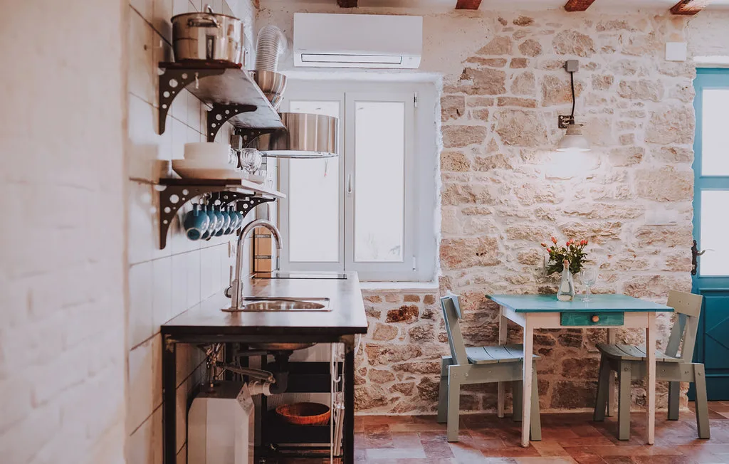 Una cocina compacta con una mesa de comedor junto a una pared de piedra.