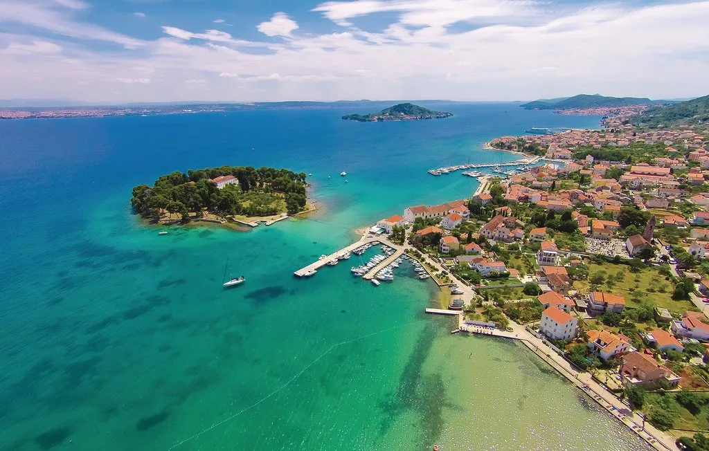 Vista aérea de un pueblo costero junto a aguas turquesas y una pequeña isla.