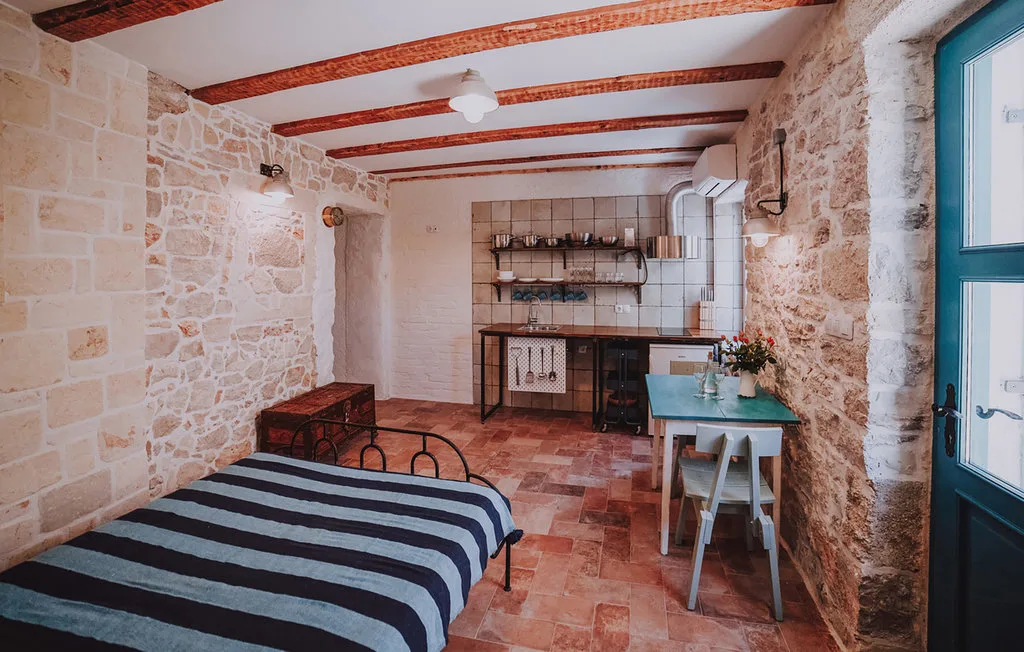 Un dormitorio rústico con una cama a rayas y una pequeña zona de cocina.