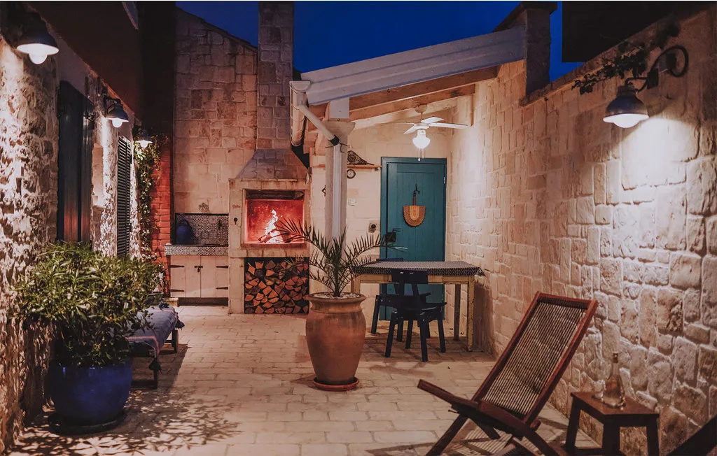 Un patio exterior de piedra con una mesa, sillas y plantas en macetas.