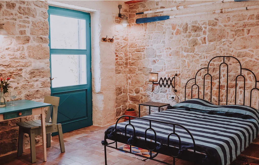 Un dormitorio con una cama a rayas junto a una puerta y ventana turquesas.