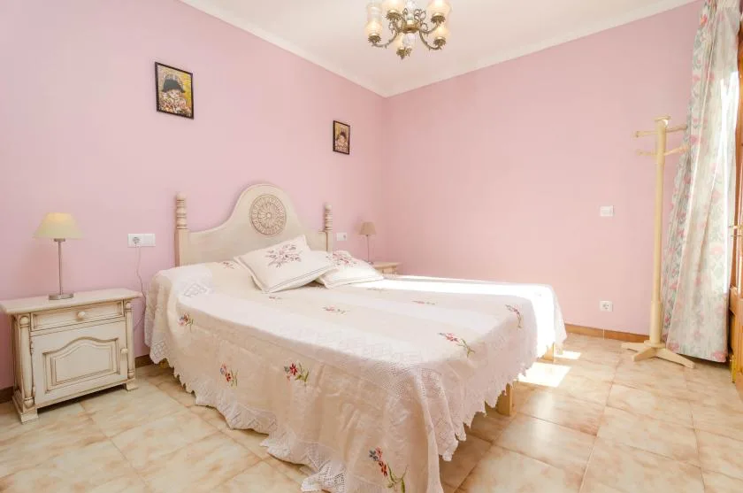 Un dormitorio con una cama, mesitas de noche y paredes rosas.