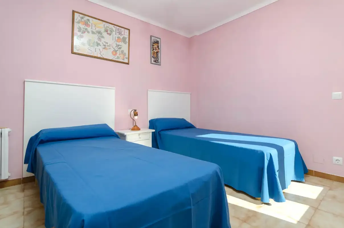 Un dormitorio rosa con dos camas cubiertas con ropa de cama azul.