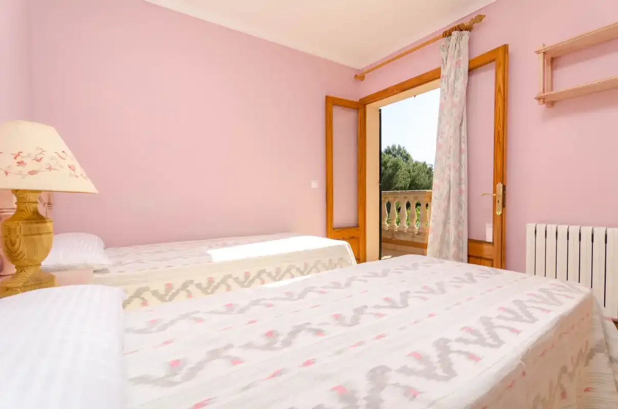 Un dormitorio con dos camas y una puerta abierta que da a un balcón.