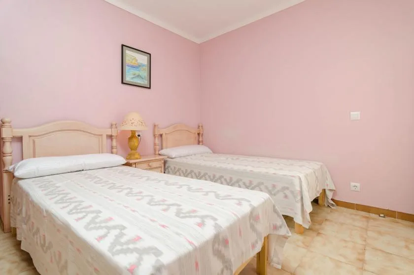 Un dormitorio con dos camas y paredes rosas.