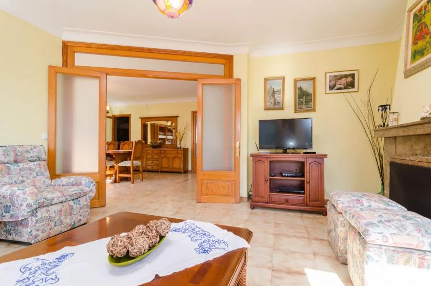 Una sala de estar con televisor y asientos alrededor de una mesa de centro.
