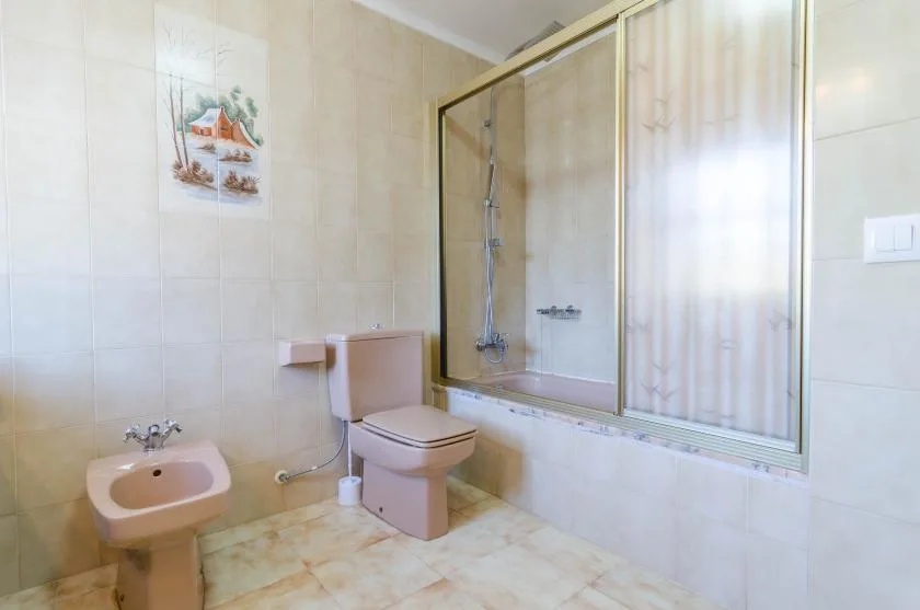 Un baño alicatado con ducha, inodoro y lavabo.