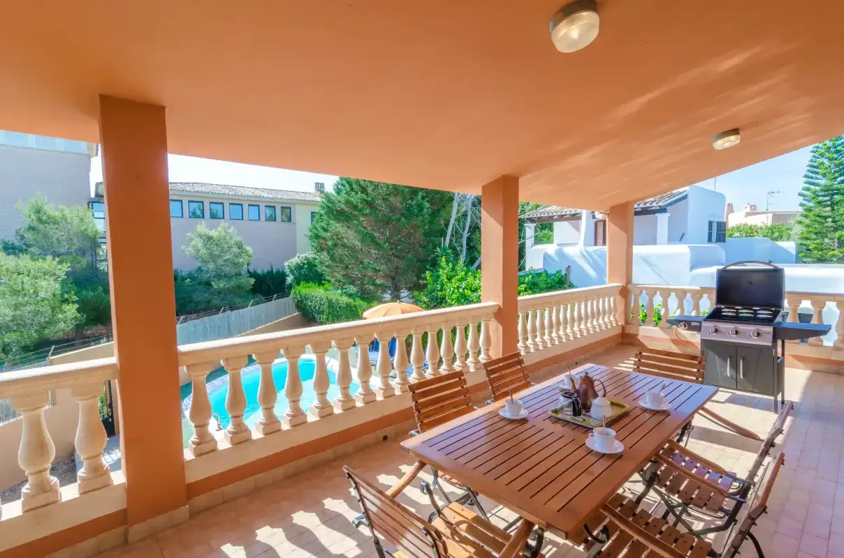 Una terraza cubierta al aire libre con mesa de comedor de madera y barbacoa.