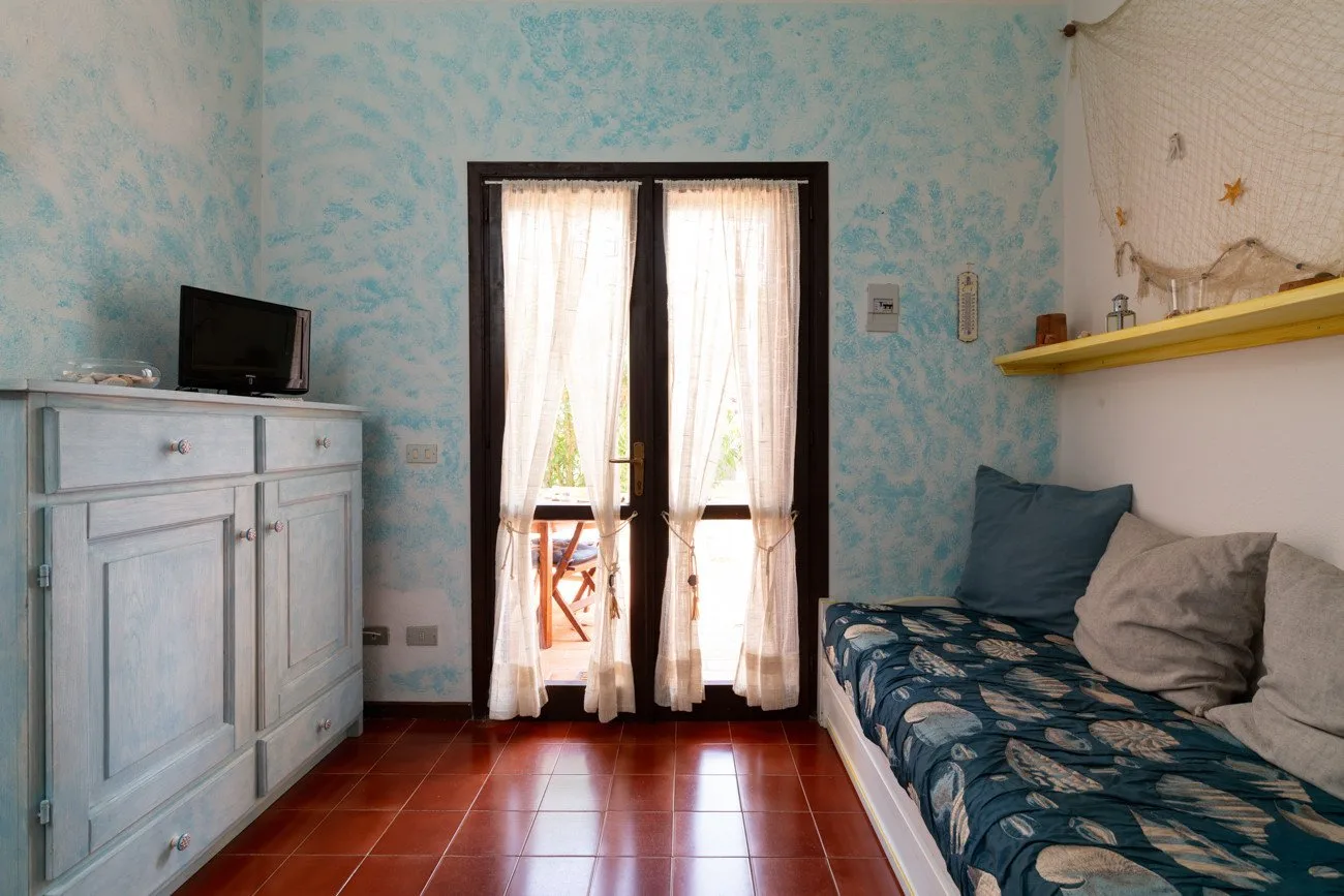 A small sitting room with a cushioned daybed and curtained glass doors.