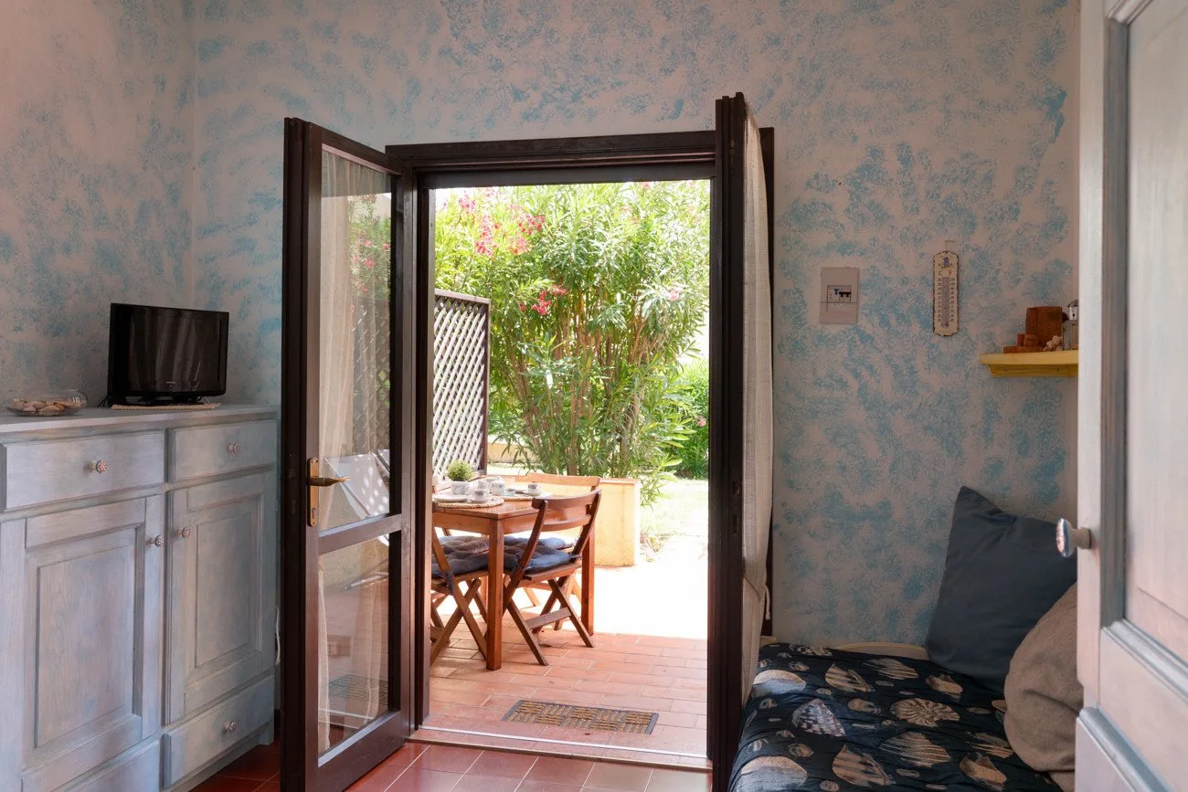 A room opens onto a patio with a small outdoor table and seating.
