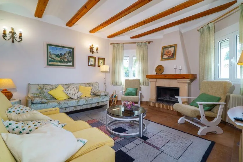 A bright living room with seating around a glass coffee table and fireplace.