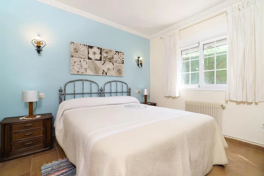 A bedroom with a large bed, bedside tables, and a window with curtains.
