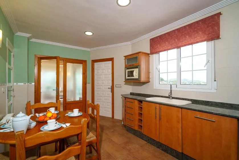 A kitchen and dining area with a wooden table set beside the counter.