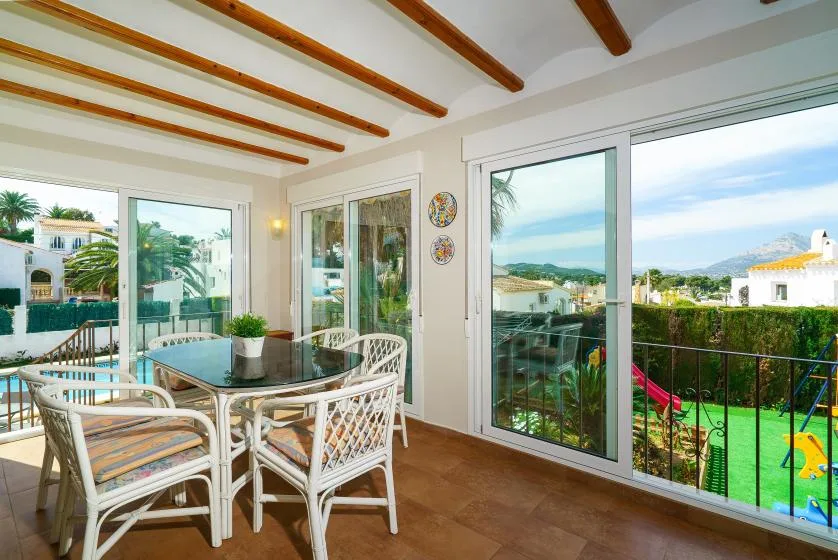 A bright dining area opens onto a balcony with garden and coastal views.