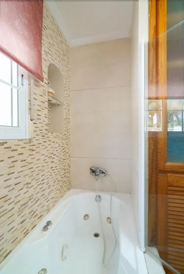 A bathroom with a built-in bathtub and tiled walls.