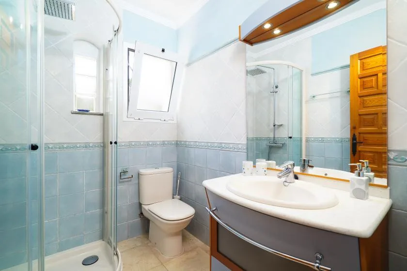 A bright bathroom with a glass shower and a large sink beneath a mirror.