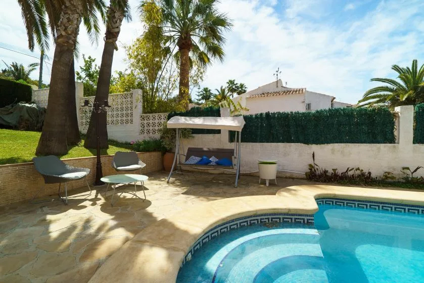 Outdoor pool area with curved steps, seating, and palm trees.