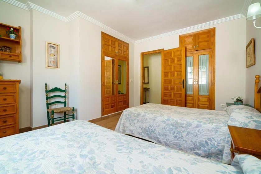 A bedroom with two beds and wooden doors along the back wall.