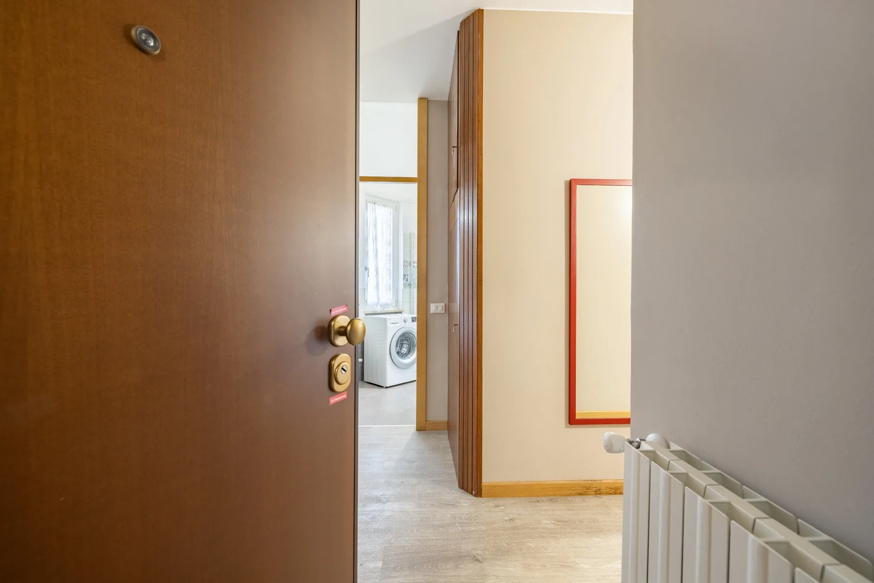 A hallway with an open door, a radiator, and a washing machine visible beyond.