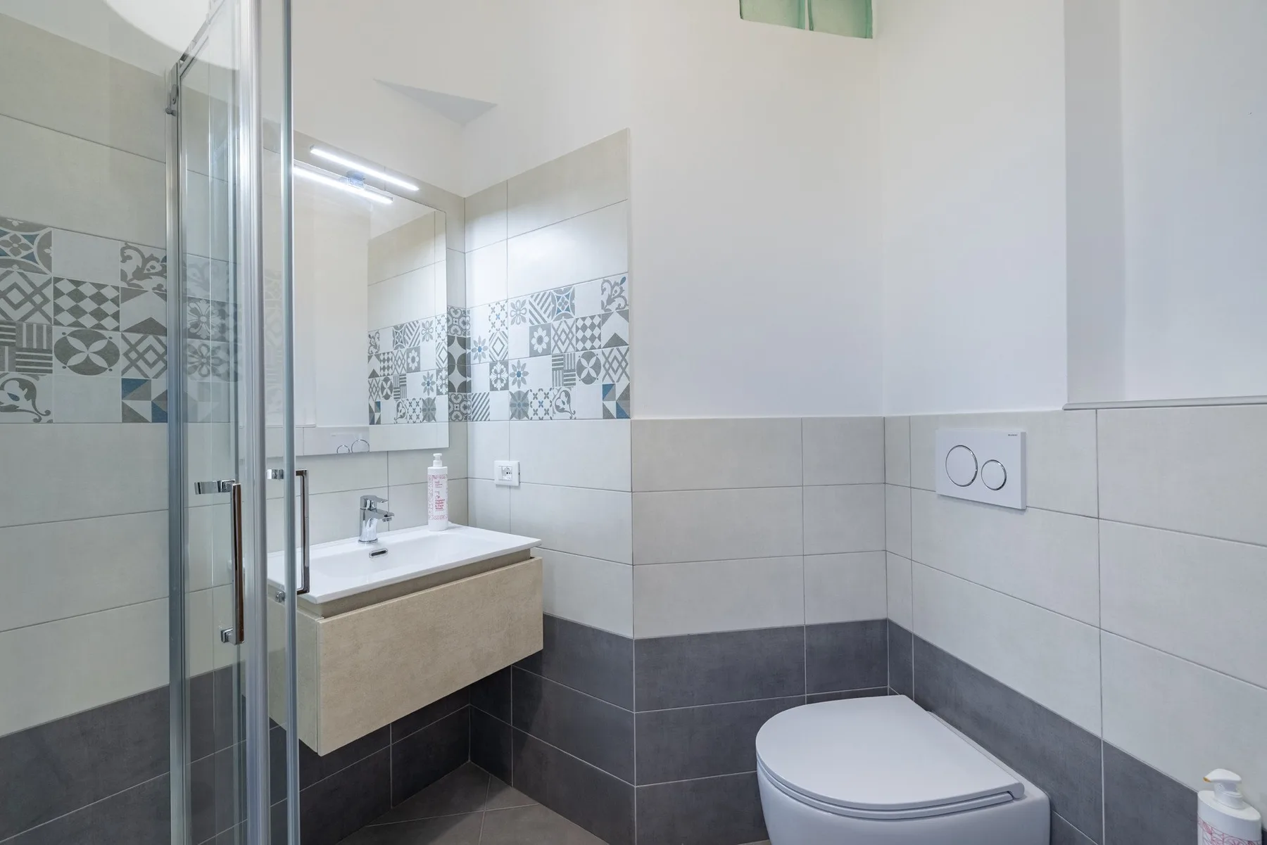 A modern bathroom with a sink, mirror, and toilet.