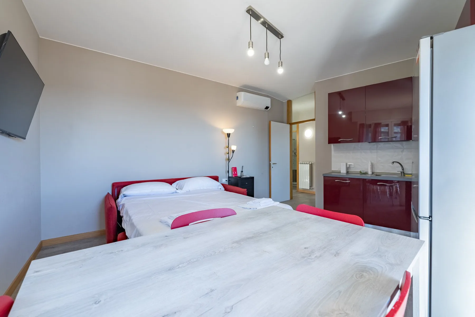 A bedroom with a bed beside a compact kitchen area.