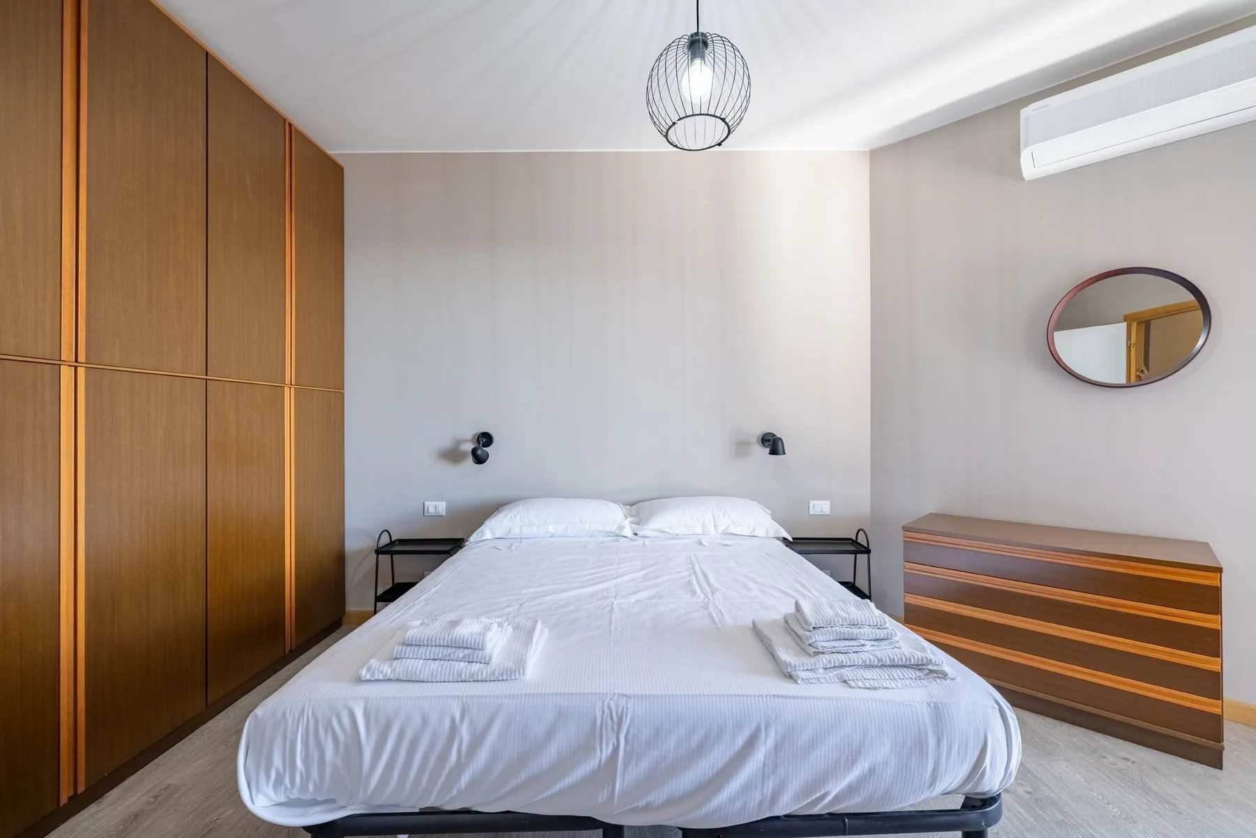 A bedroom with a neatly made bed and wooden storage cabinets.