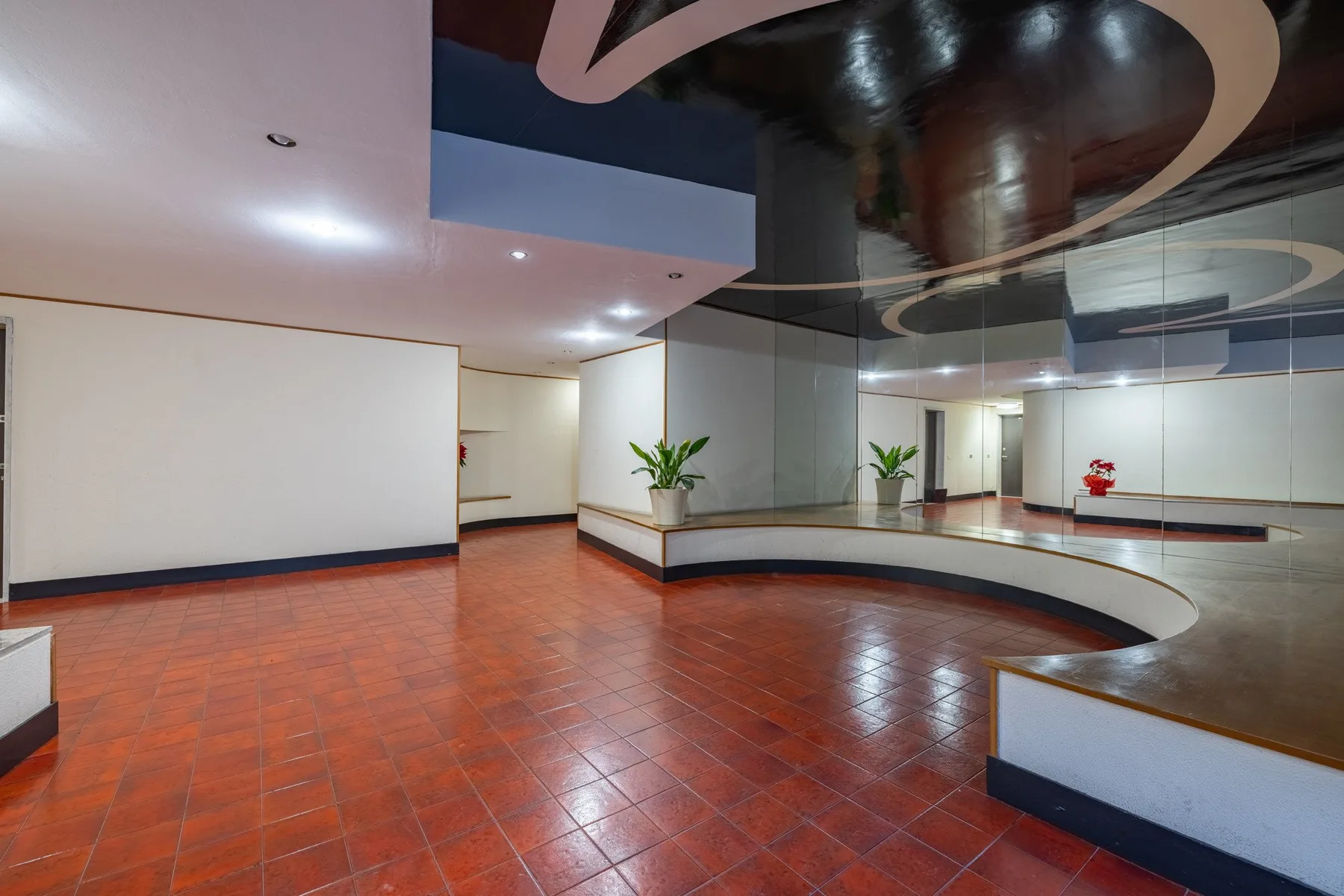 A spacious interior lobby with glossy tiled flooring and mirrored walls.