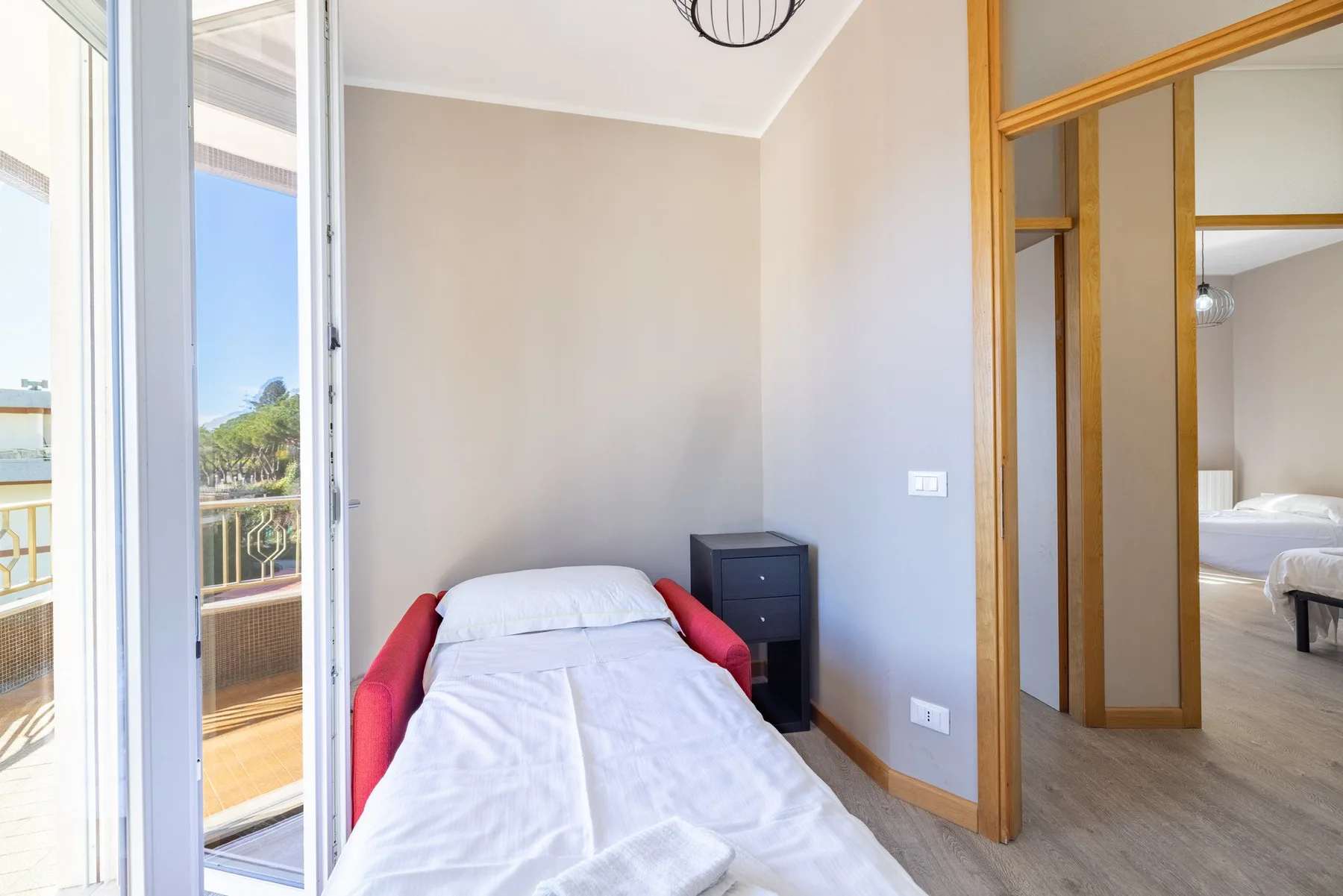 A compact bedroom with a single bed beside a glass balcony door.