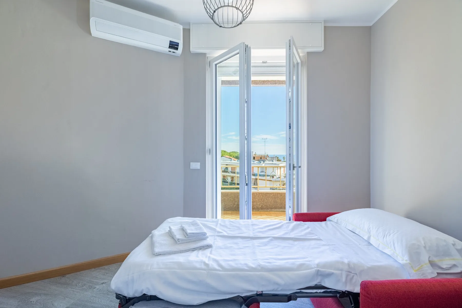 A bedroom with an unmade bed and open doors leading to a balcony.