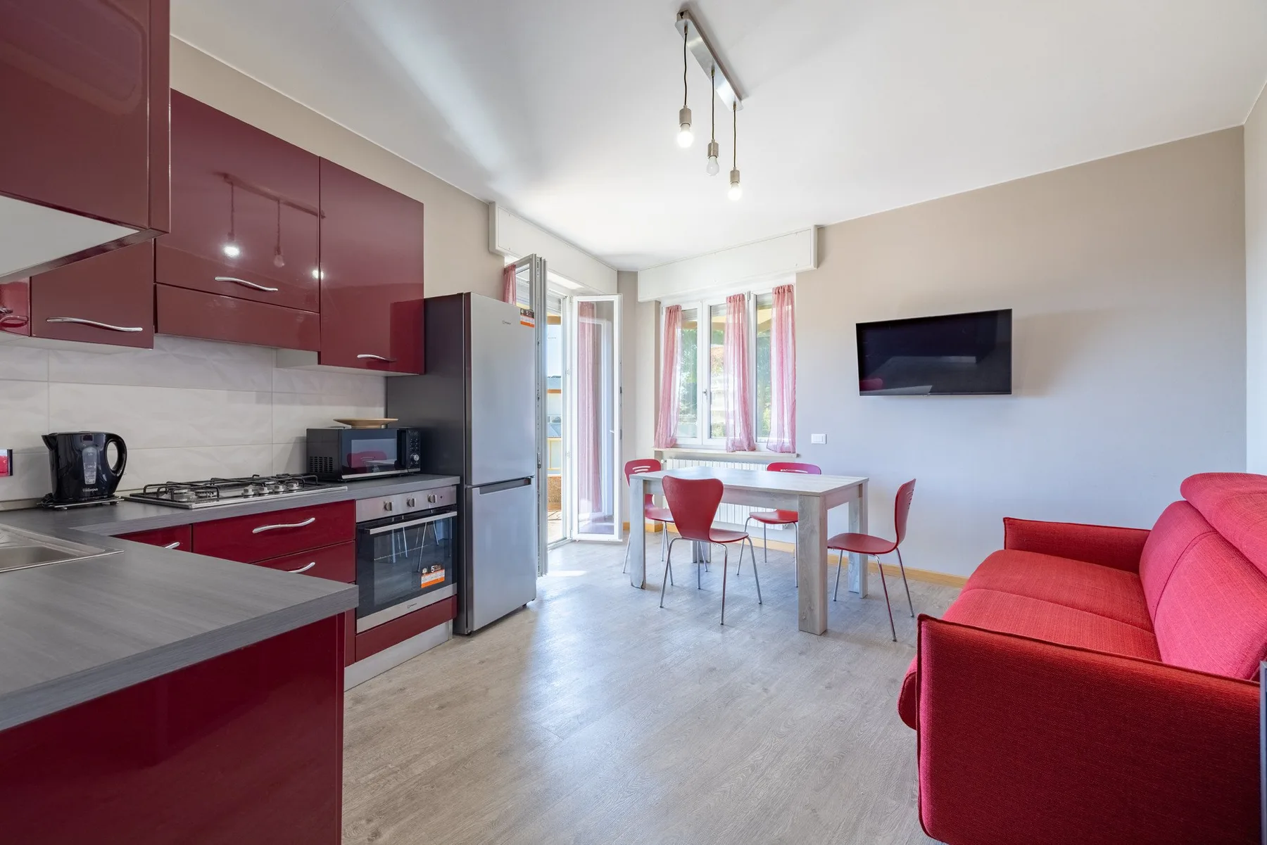Open-plan living area with a red sofa, dining table, and kitchen.