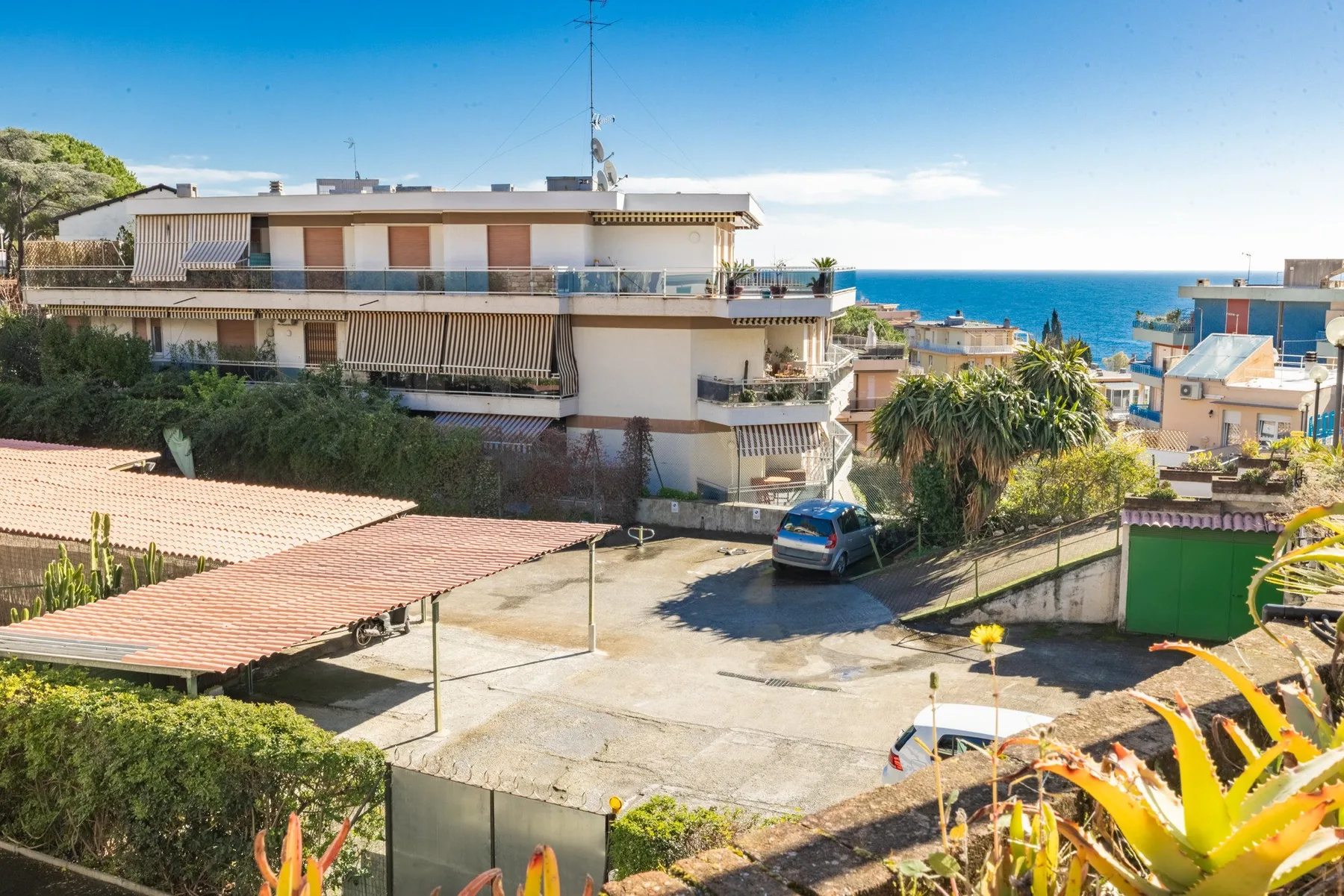 A coastal residential neighborhood with apartment buildings and the sea in the background.