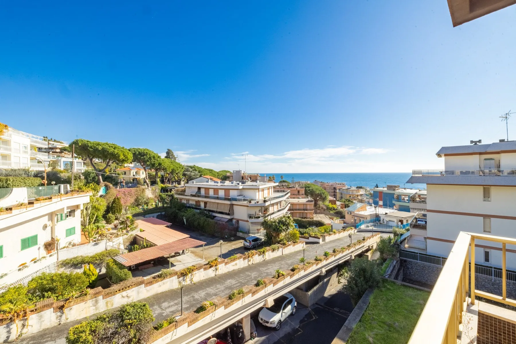 A coastal neighborhood with low-rise buildings and the sea visible in the distance.