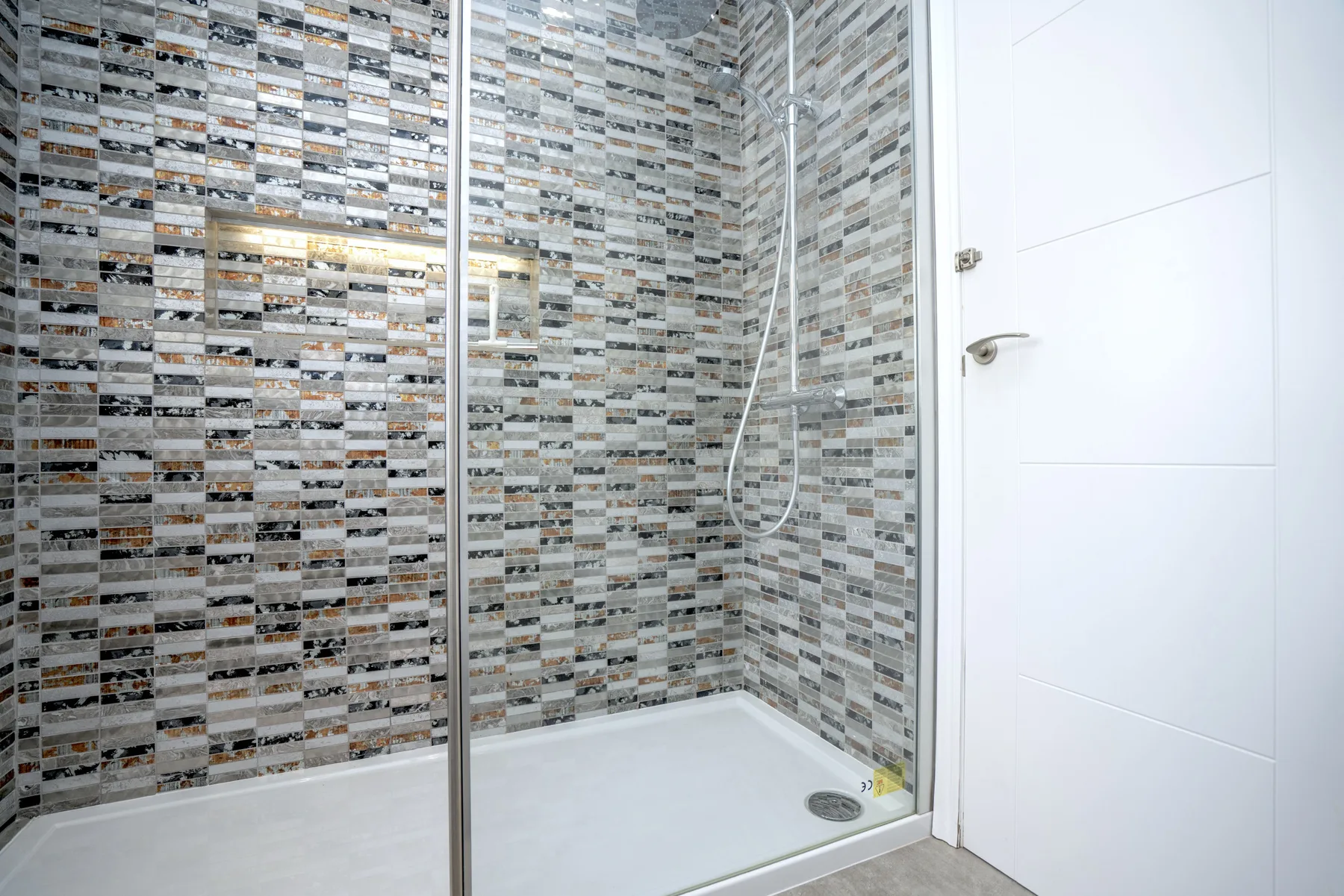 A tiled shower area with a white shower tray and glass screen.