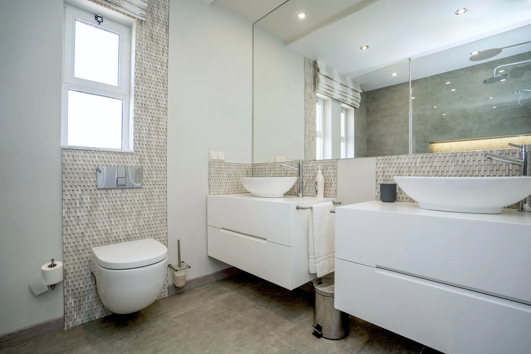 A modern bathroom with a wall-mounted sink and a glass shower.