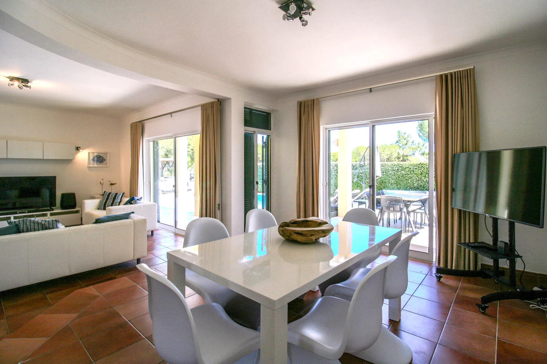 A bright living and dining area opens onto a patio through large glass doors.