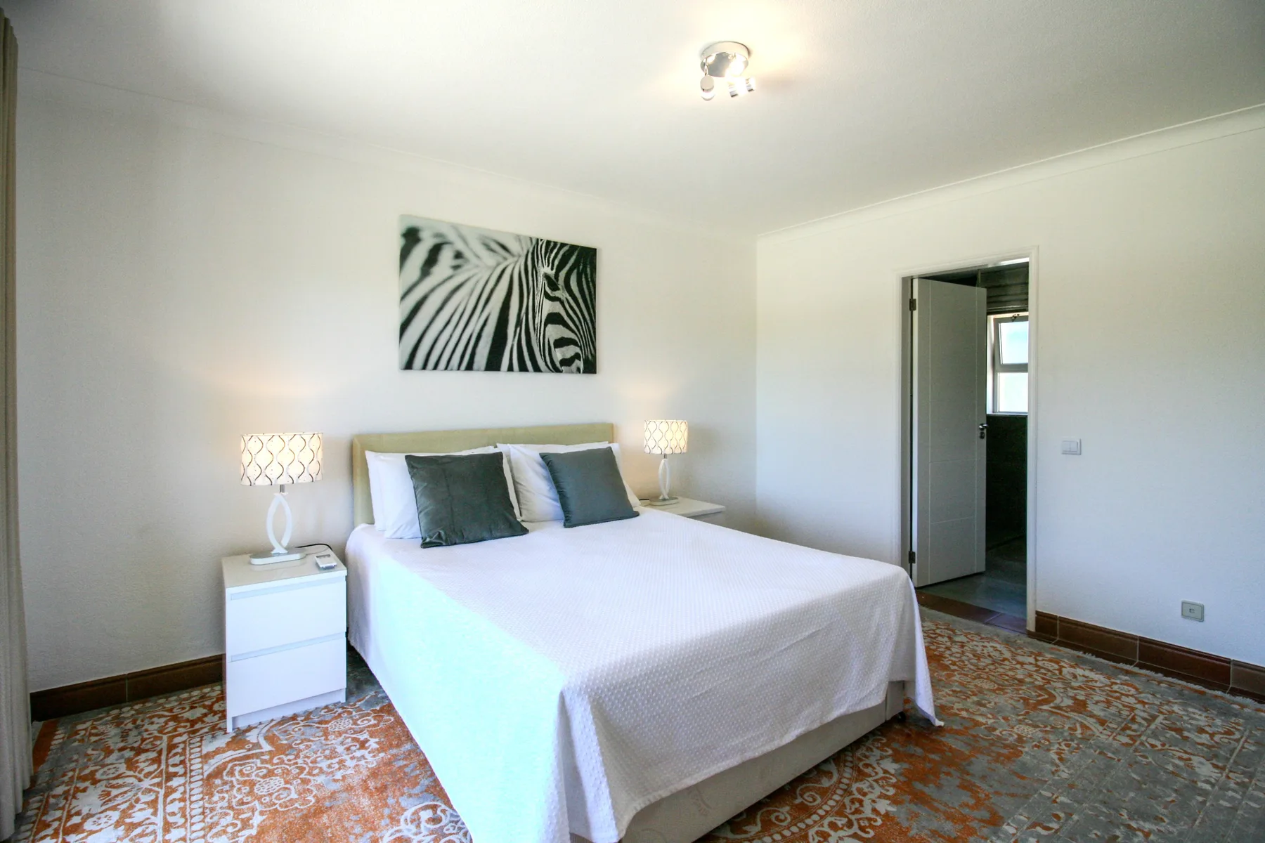 A bedroom with a double bed, bedside tables, and abstract wall art.