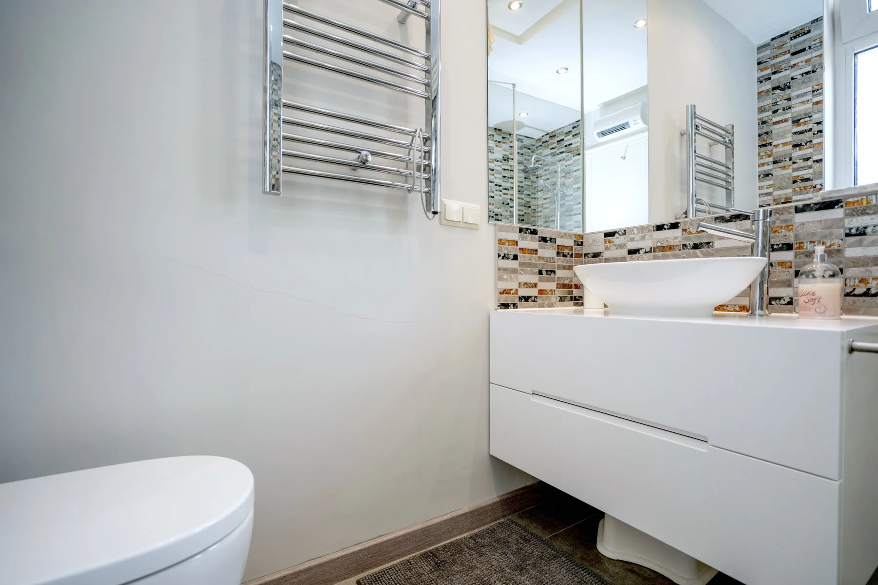 A bathroom with a white vanity, vessel sink, and wall mirror.