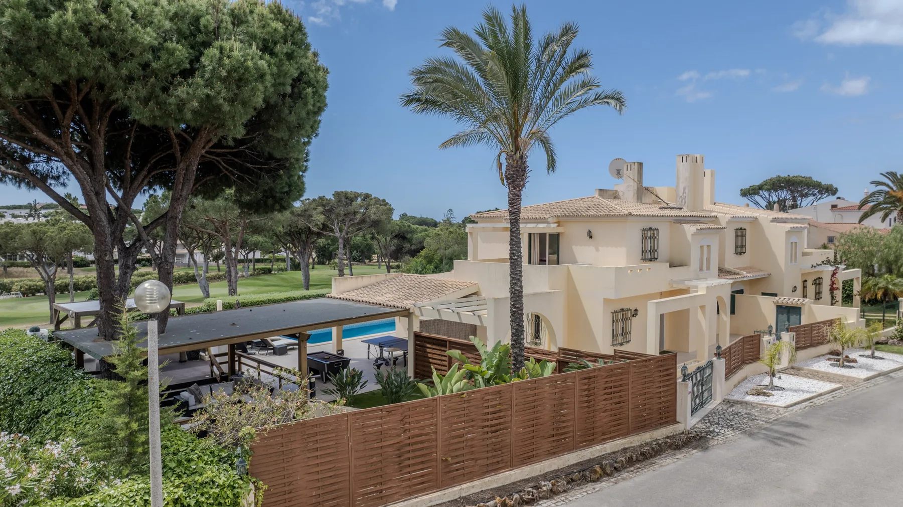 A residential complex with a fenced swimming pool and surrounding trees.