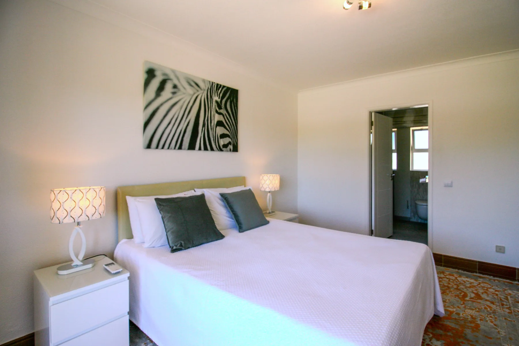 A bedroom with a bed, bedside tables, and abstract wall art.