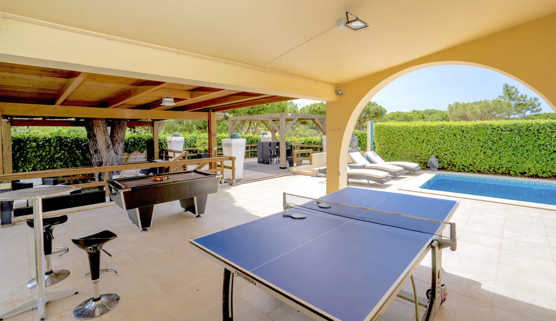 A covered outdoor recreation area with a table tennis table and pool.