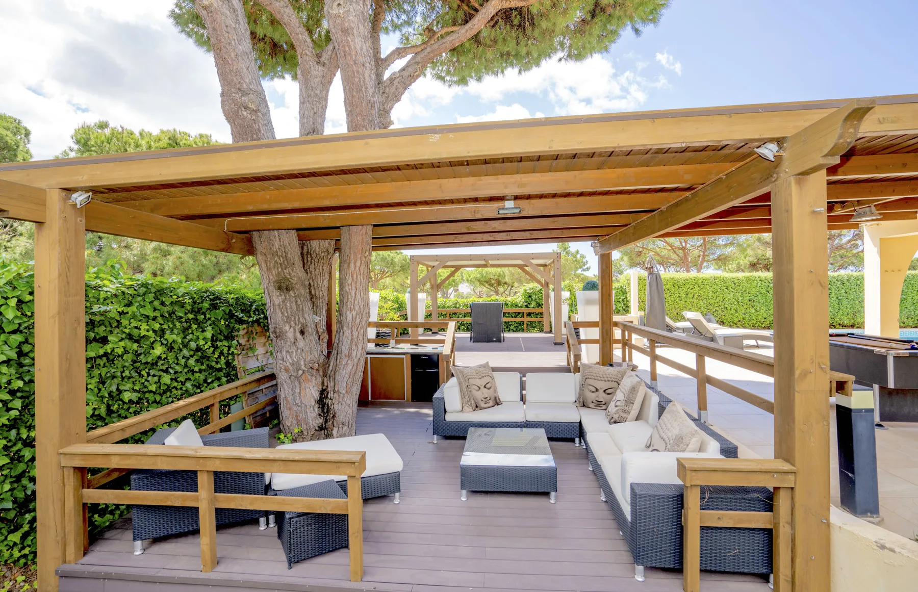 A covered outdoor seating area with cushioned furniture and wooden railings.