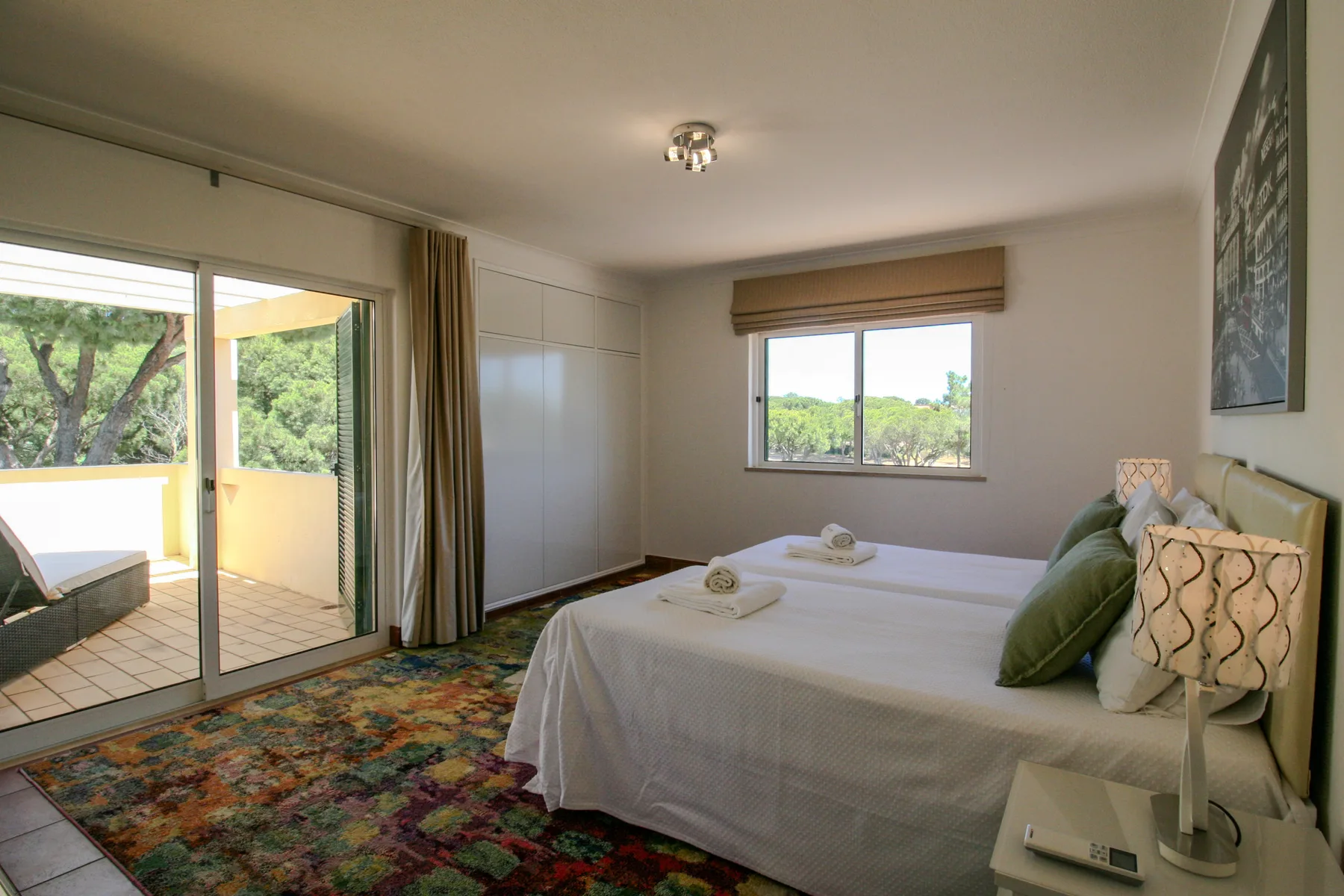 A bedroom with two beds and a sliding glass door opening onto a balcony.