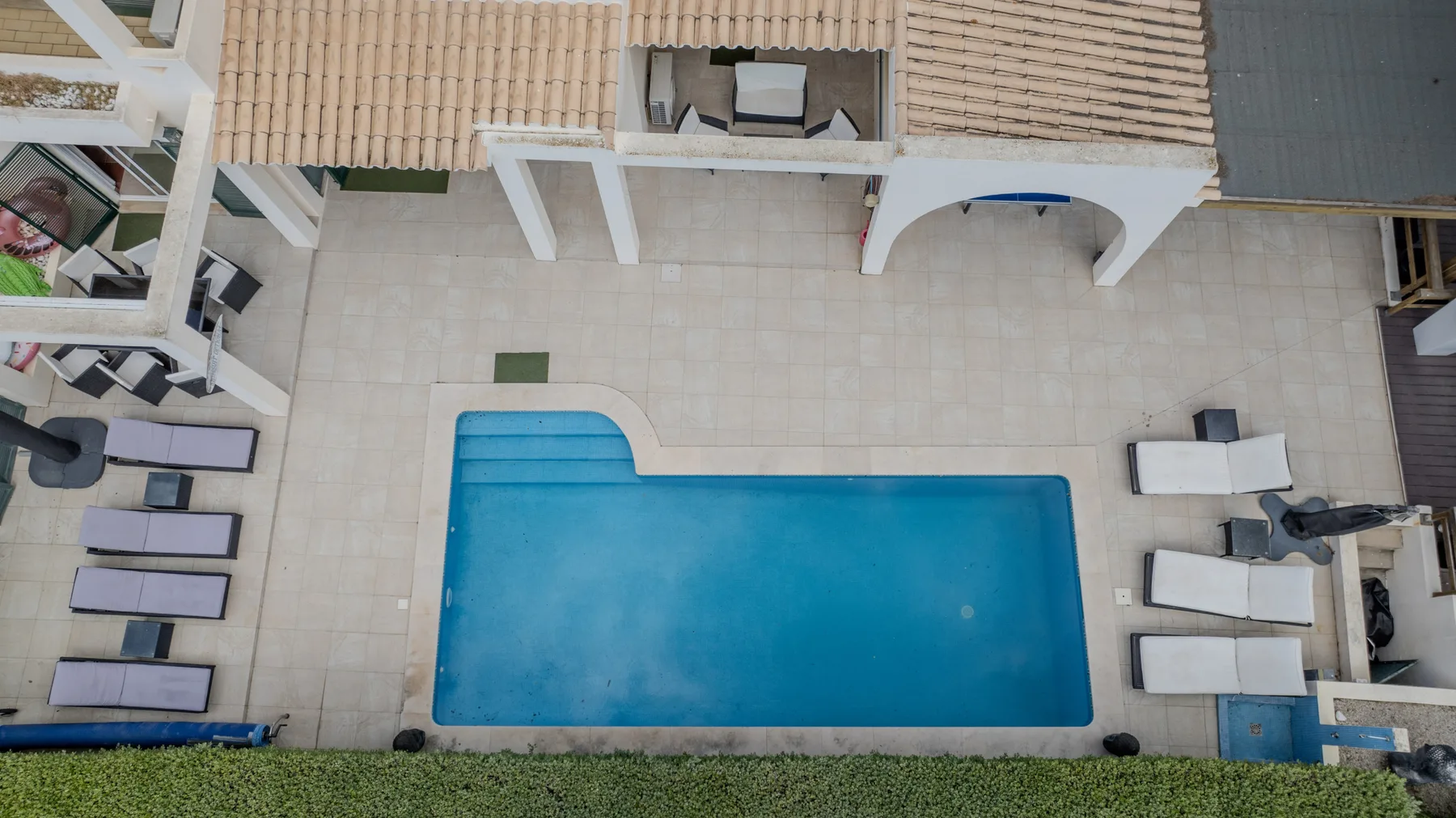An overhead view shows a rectangular swimming pool beside a tiled patio.