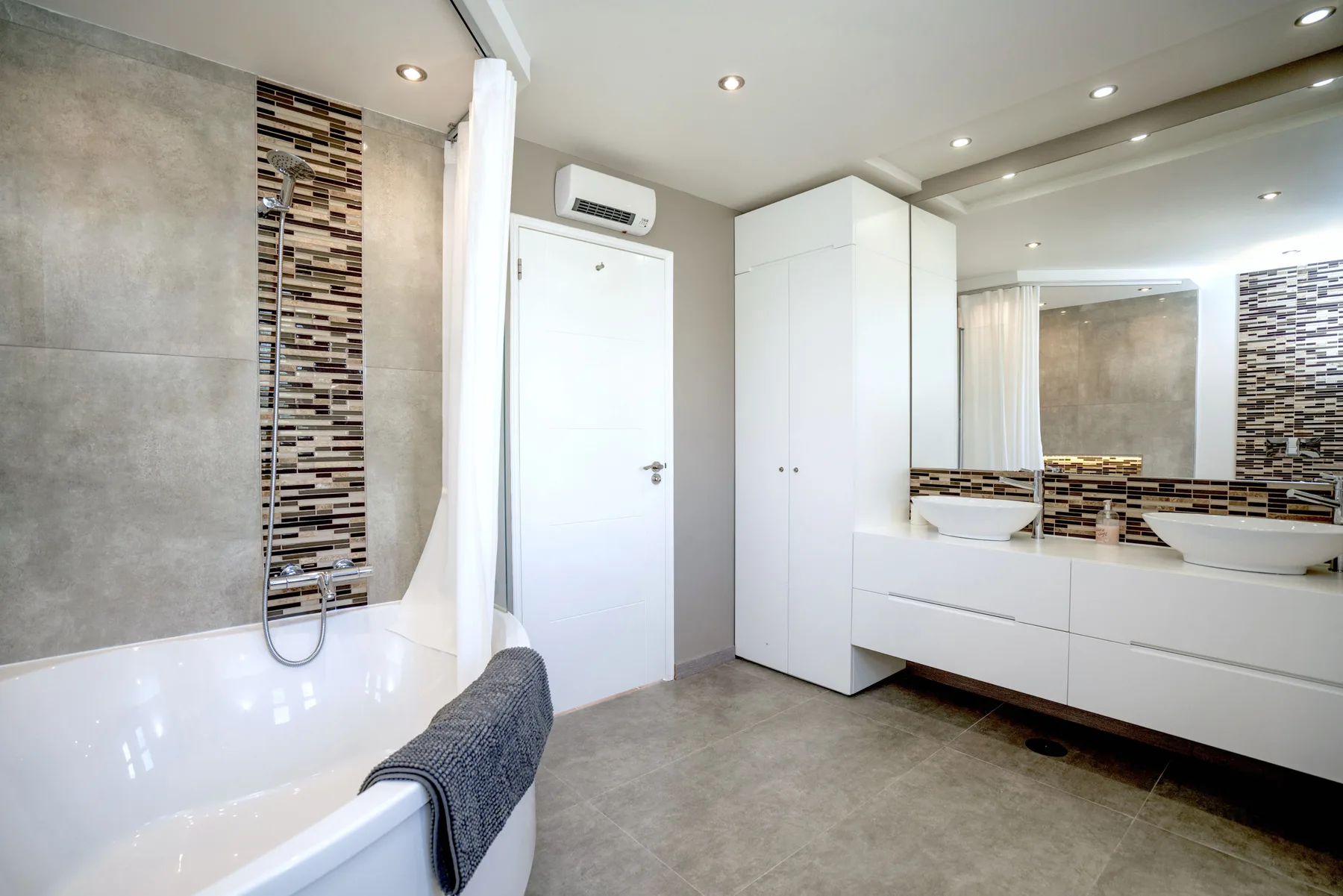 A modern bathroom with a bathtub, vanity, and large mirror.